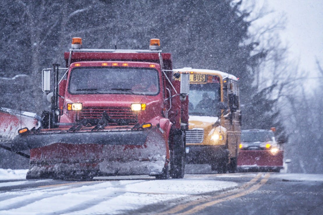 Snow plough clearing road for school bus